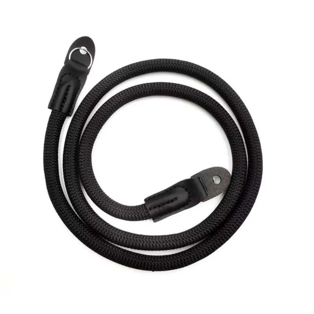 Black adjustable camera and DSLR shoulder strap coiled on a white background