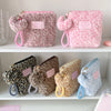 Pink leopard print makeup bags with fuzzy appliqués and pink straps displayed on a white shelf.