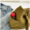 A mustard green corduroy fabric is shown folded around a glass bottle on a white surface.