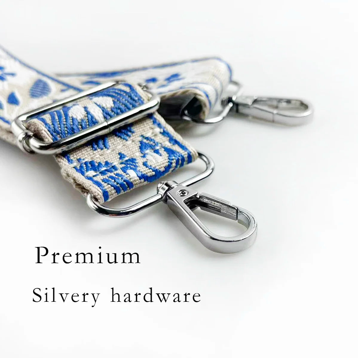 Close-up of a premium silvery hardware strap featuring blue and white floral jacquard fabric on a bag.