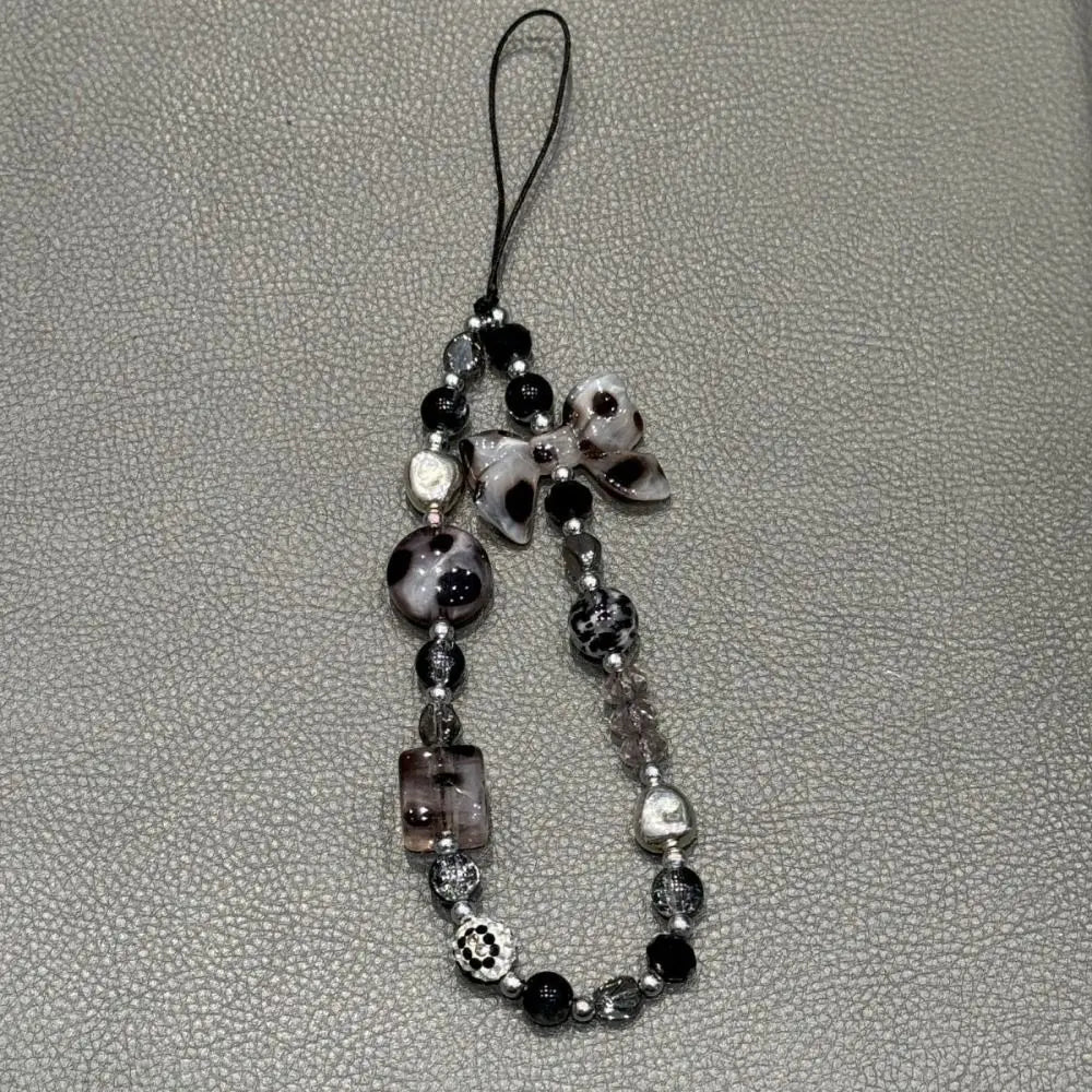 A black and white leopard print bowknot phone lanyard featuring heart-shaped beads.