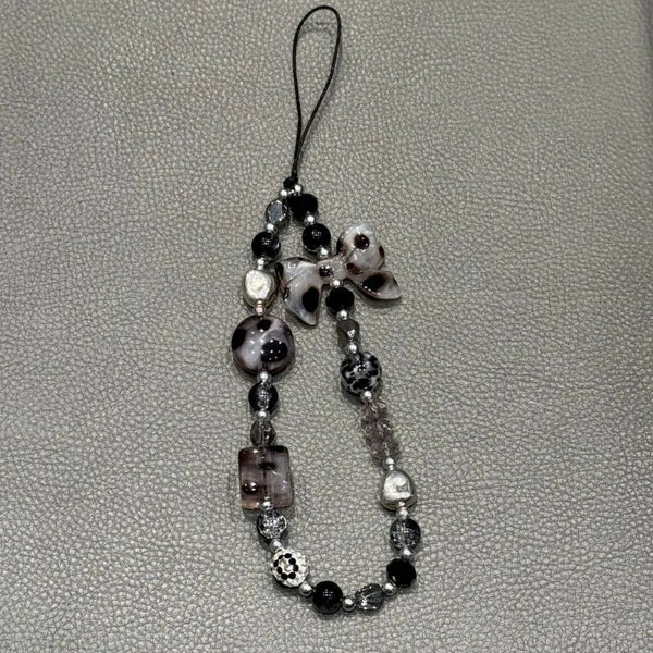 A black and white leopard print bowknot phone lanyard featuring heart-shaped beads.