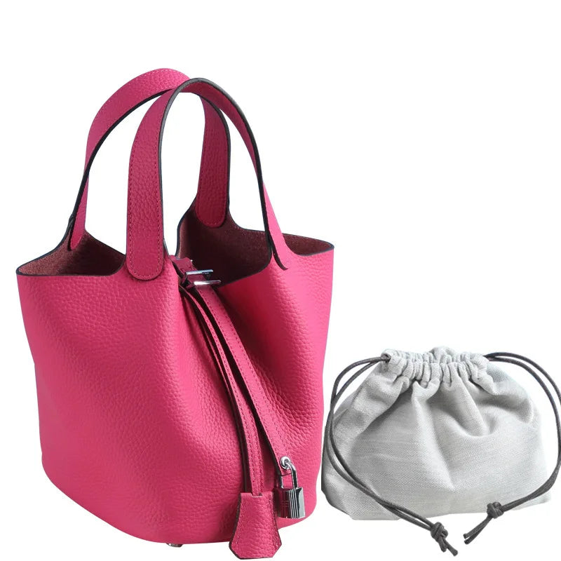 Helles pinkes Leder-Bucket-Bag mit schwarzen Riemen und einer passenden hellgrauen Schnurtasche.