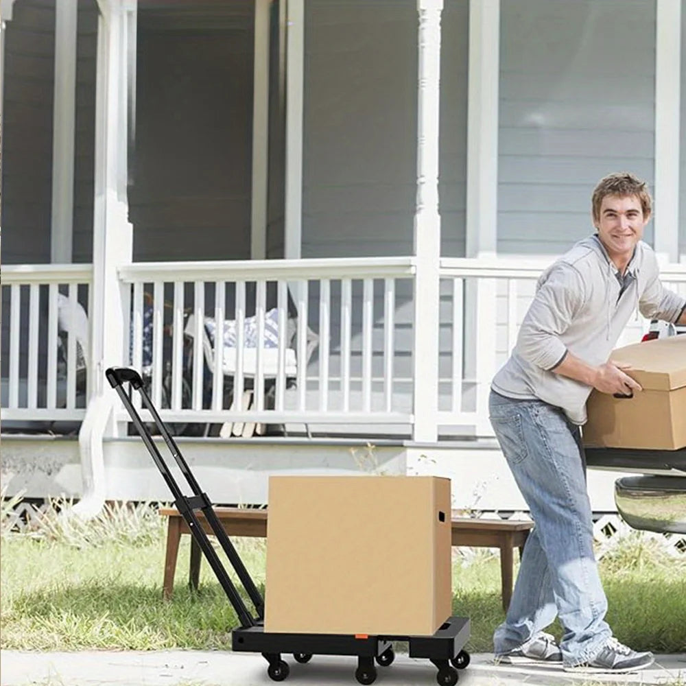 A man is loading a cardboard box onto a heavy duty folding hand truck luggage cart outside a house.