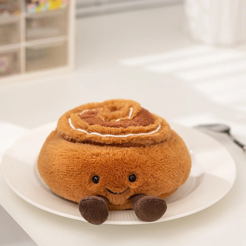 A round, brown cartoon character plush toy with a coiled top and small feet sitting on a white plate.