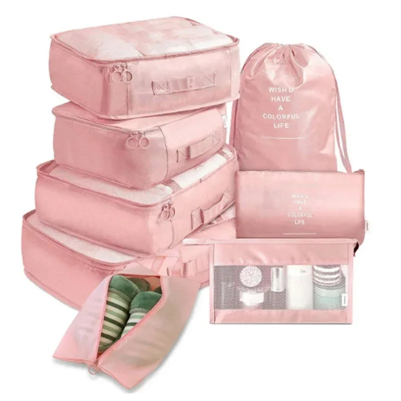 A set of pink mesh packing cubes and a matching drawstring bag for travel organization.