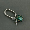 A silver keychain featuring a green resin die with numbered faces and a star charm