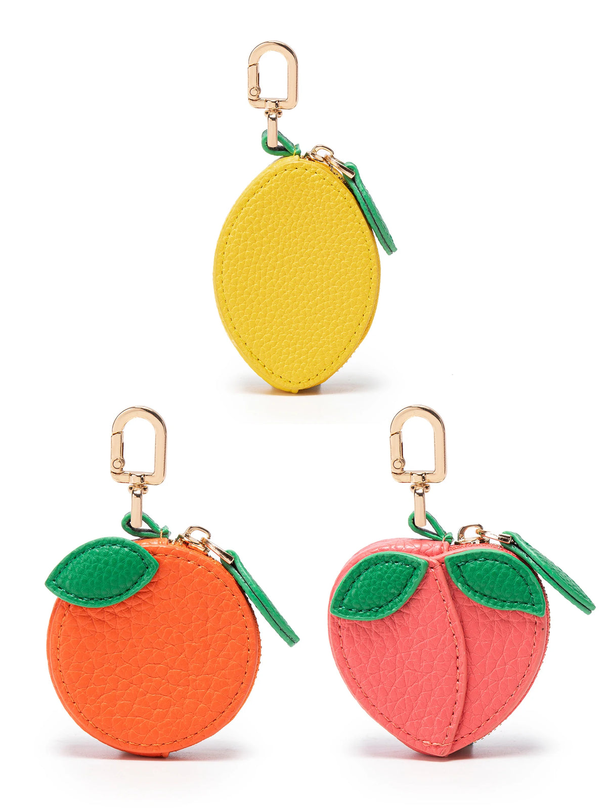 A set of three fruit-shaped coin purse keychains in yellow, orange, and pink.