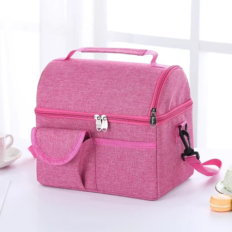 A pink reusable insulated lunch bag with a zippered compartment and a separate pocket is shown on a white surface.