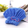 Lazo de microfibra azul brillante para el pelo y toalla de baño junto a dispensador de jabón y toallas enrolladas.