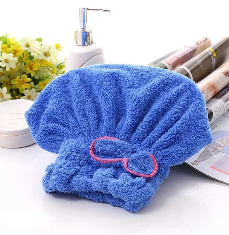 Lazo de microfibra azul brillante para el pelo y toalla de baño junto a dispensador de jabón y toallas enrolladas.