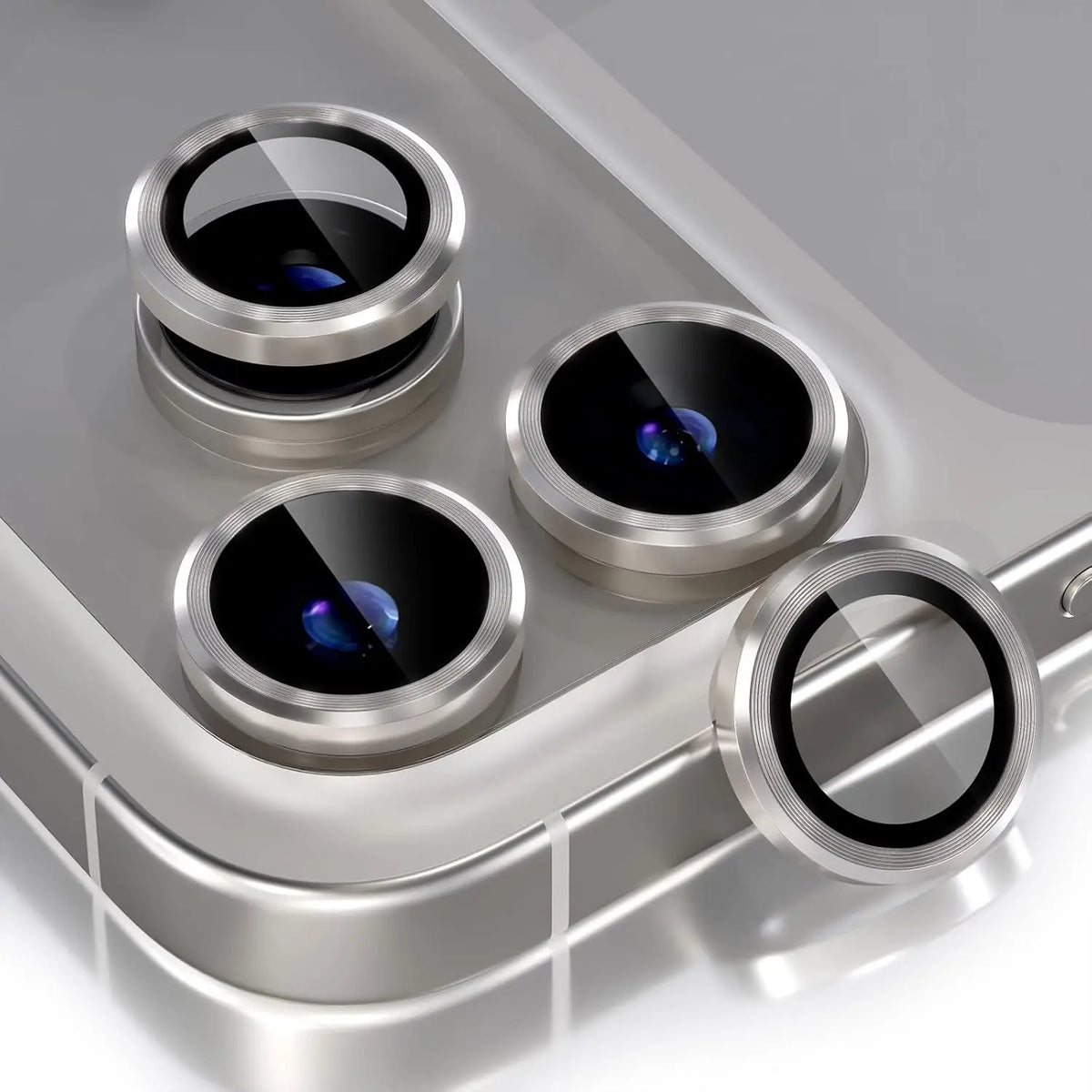 A silver metal frame product showing several camera lenses and a detached lens on a gray surface.
