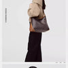 A woman is shown holding a gray geometric embroidery hobo shoulder bag with brown leather trim.