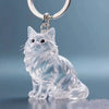 A clear glass pendant shaped like a sitting cat, attached to a silver keychain ring.