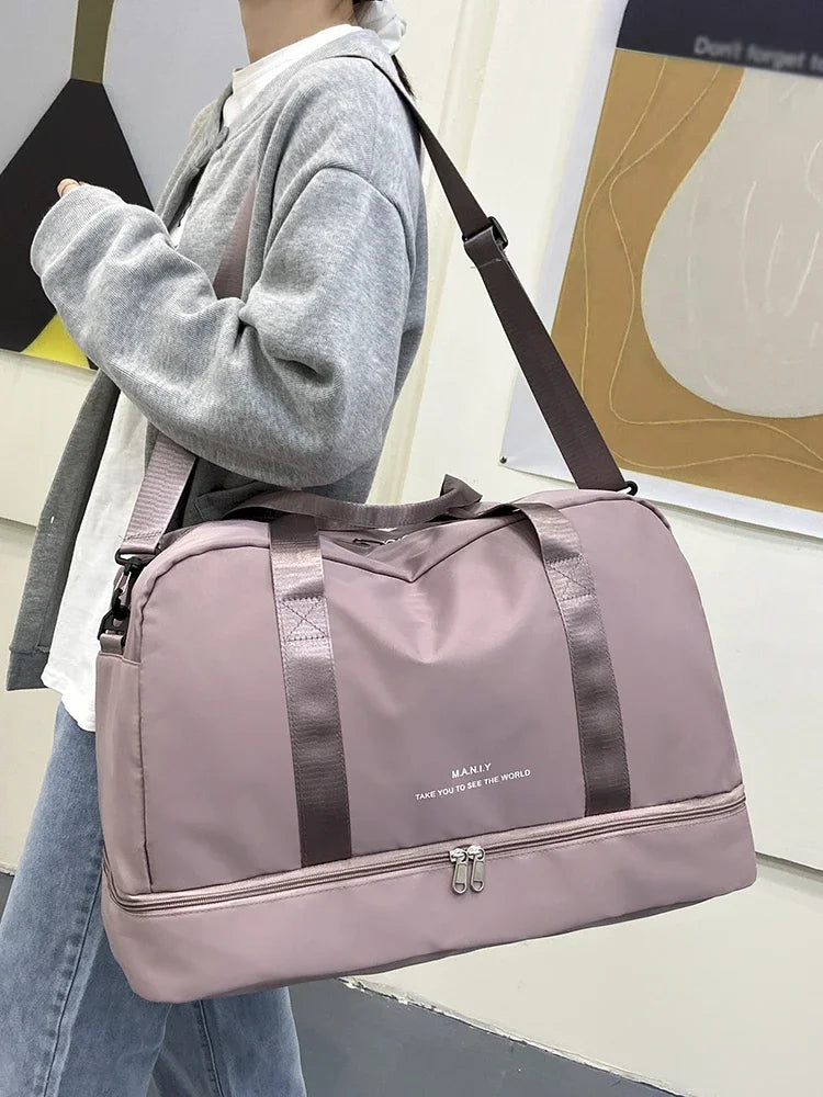 A light pink expandable nylon travel duffle bag is carried by a person, shown in a side view.