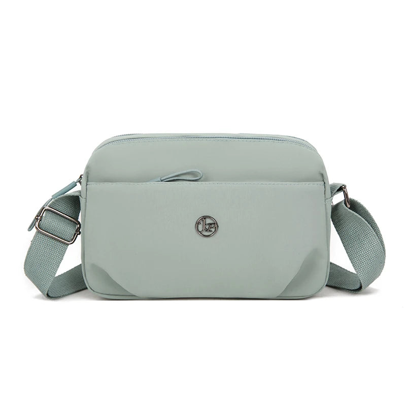 Bolso cruz impermeable de nylon verde salvia claro con solapa y correa ajustable.