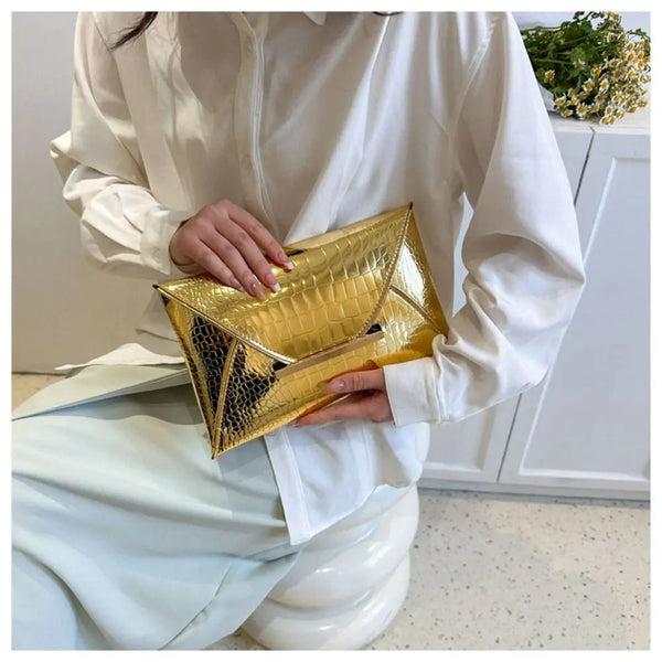 A person wearing a white shirt holds a gold crocodile pattern coin purse clutch.