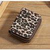 A brown and black leopard print double zipper wallet resting on a wooden surface.