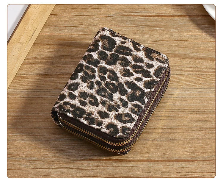 A brown and black leopard print double zipper wallet resting on a wooden surface.