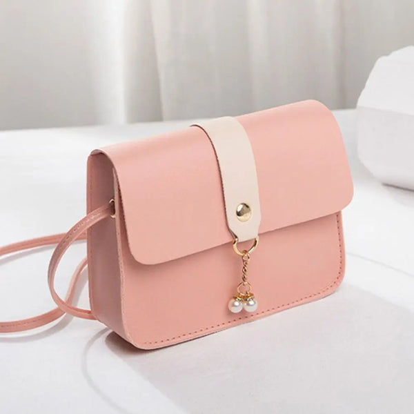 Hellrosa modisches quadratisches Crossbody-Taschen mit beigem Riemchen und goldener Kettchenverzierung auf weißem Untergrund.