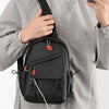 Un homme en veste grise tient un sac de sport noir avec des accents orange.