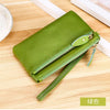 A lime green genuine leather wristlet clutch wallet with a zipper closure resting on a wooden surface.