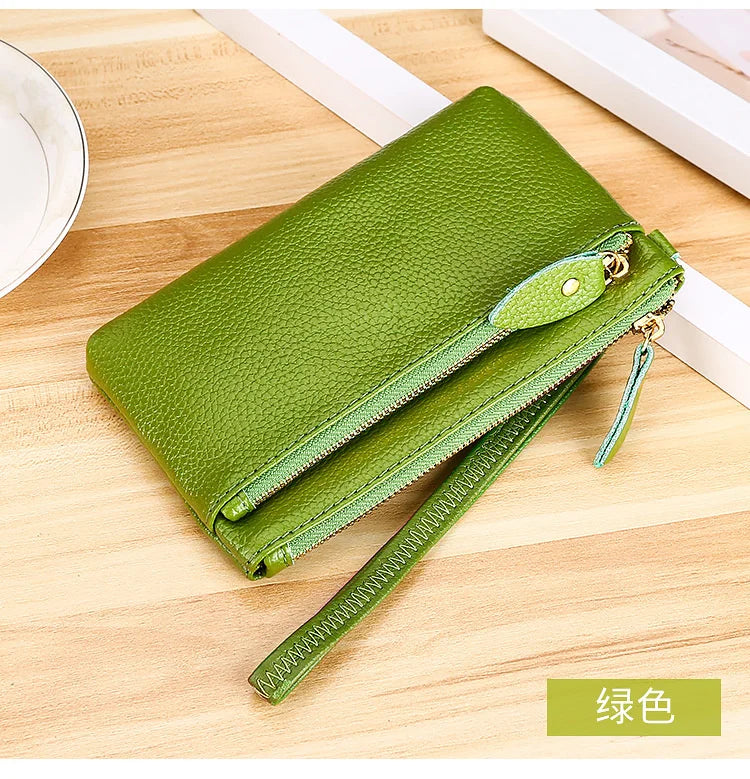A lime green genuine leather wristlet clutch wallet with a zipper closure resting on a wooden surface.