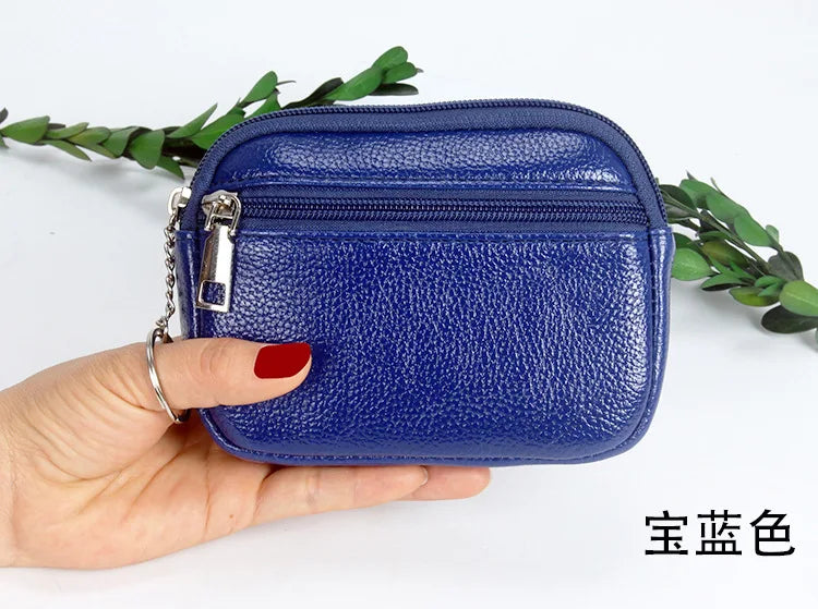 A hand holds a dark blue PU leather mini wallet with a silver keychain against a white background.
