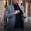 A man wearing a gray plaid blazer and black turtleneck holds a carbon fiber microfiber wallet.