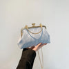 Clutch de noche con lazo brillante azul claro y herrajes dorados que sostiene una persona.