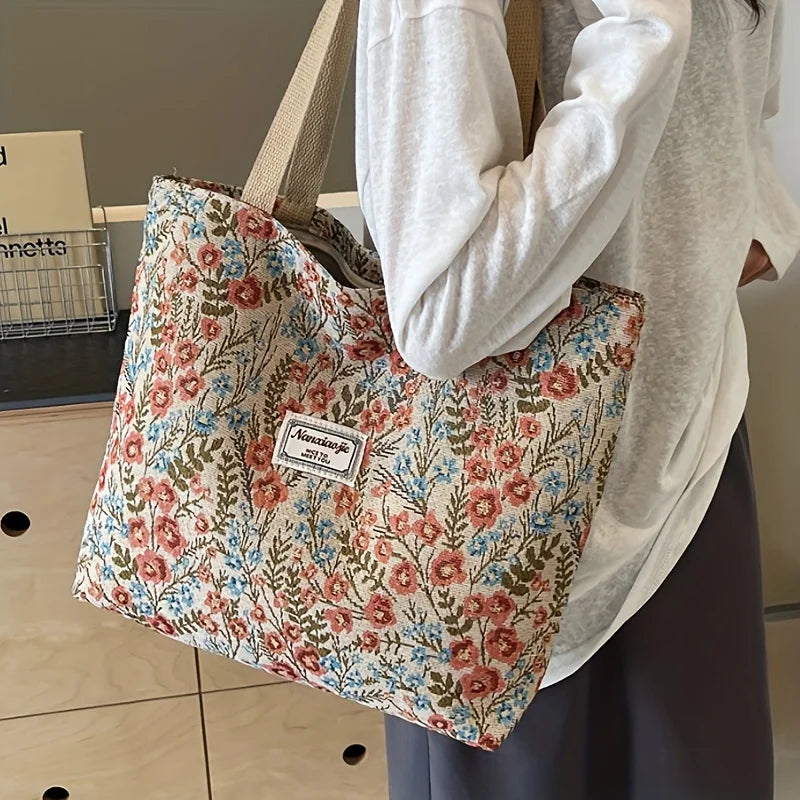 A person holds a patterned bohemian corduroy tote bag with light floral designs.