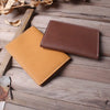 A brown leather passport and ticket holder resting on weathered wooden planks.