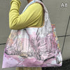 A woman holds a large, light pink and white floral print nylon shopping tote bag.