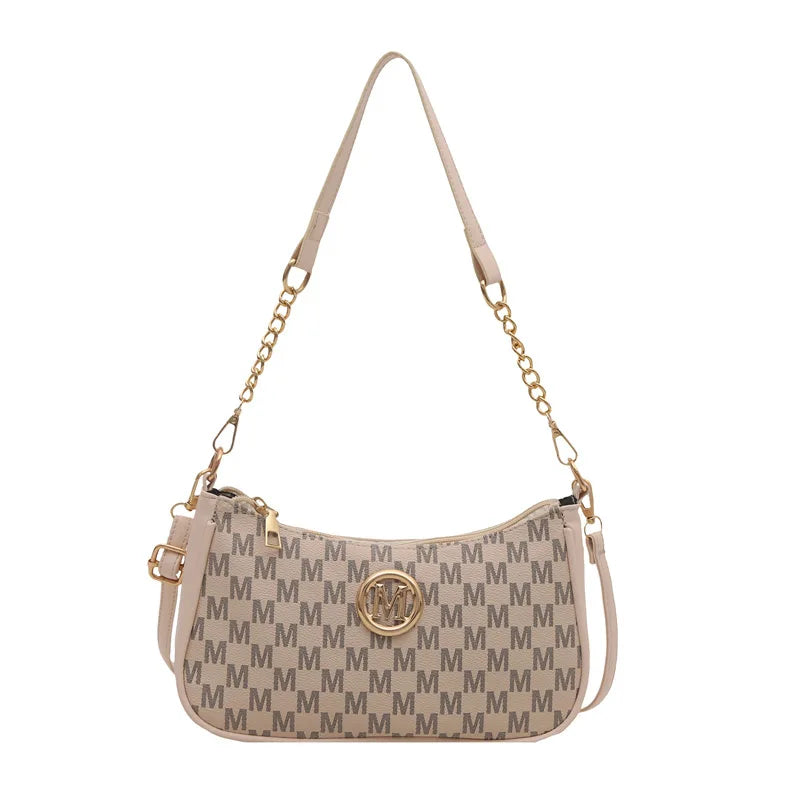 Bolso cruz beige vintage dorado con letra M, correa de cadena y herrajes dorados.