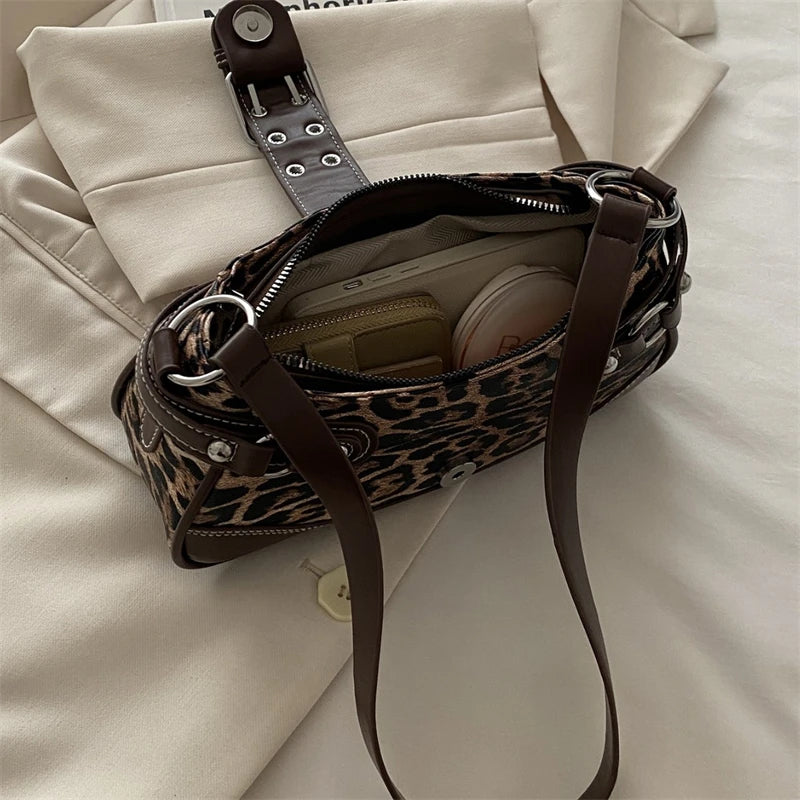 Sac à main en imitation cuir marron à imprimé léopard avec une sangle marron foncé sur un tissu beige clair.