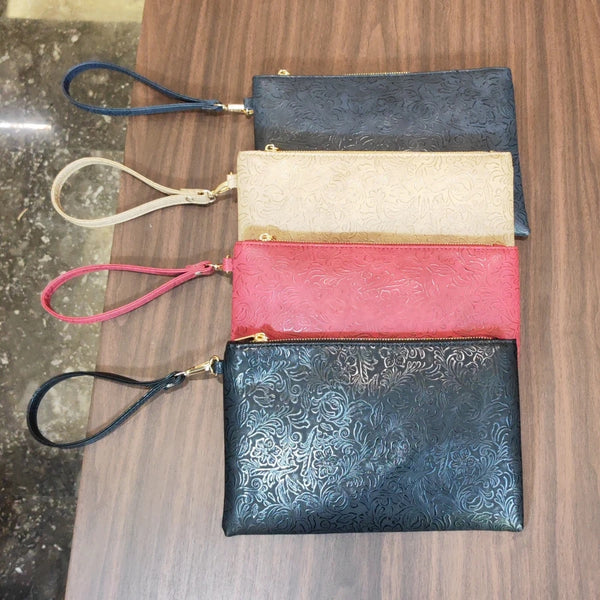 A collection of four vintage floral patterned PU leather clutch purses in shades of navy, beige, pink, and dark blue resting 