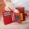 A hand holds an open red leather card holder wallet displaying various cards and cash.