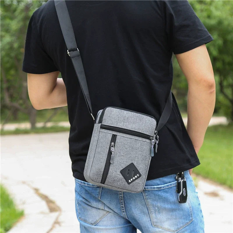 A man wearing a black t-shirt is holding a gray lightweight crossbody sling bag.