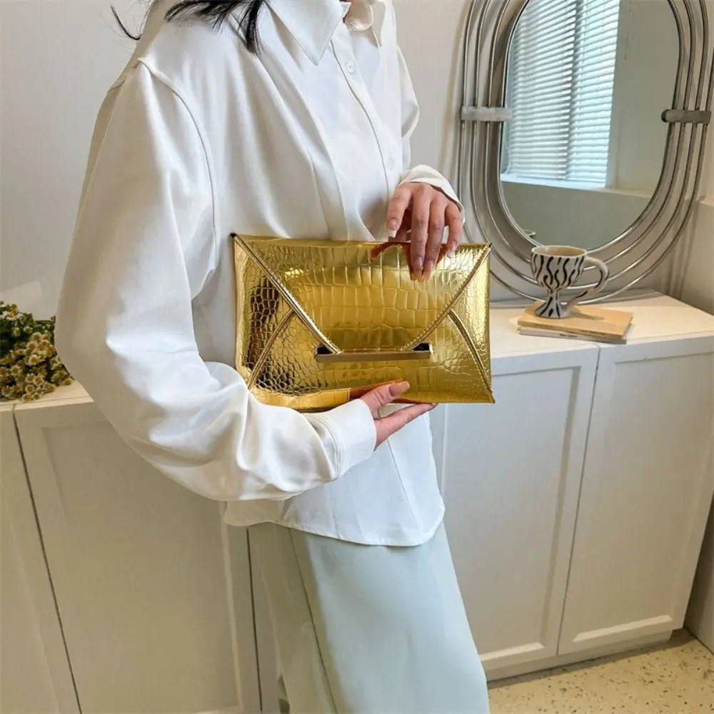 A person wearing a white shirt holds a gold crocodile pattern coin purse clutch in front of a mirror.