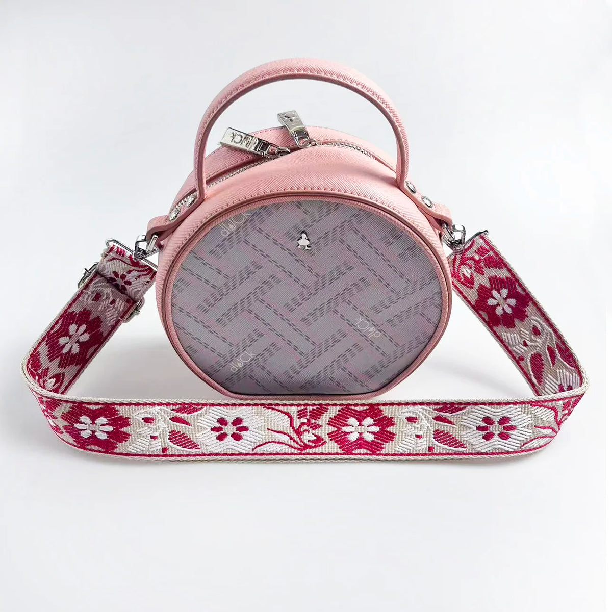 A pink crossbody bag with a patterned strap featuring red floral embroidery and a matching jacquard fabric.