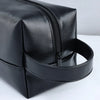 A black portable PU leather cosmetic organizer bag with a zipper and a leather strap.
