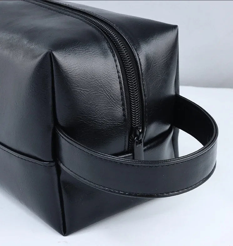 A black portable PU leather cosmetic organizer bag with a zipper and a leather strap.