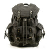 Mochila de senderismo de lona gris oscura con detalles de cuero y múltiples correas.