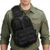 A man wearing a olive green shirt is holding a black multi-compartment crossbody and chest bag.
