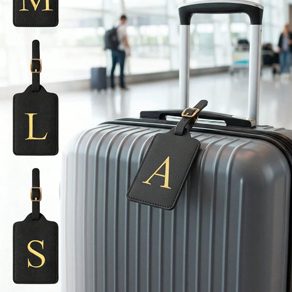 A gray suitcase with black leather luggage tags displaying the letters M, L, and S.