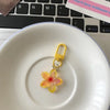 A yellow resin flower keychain resting on a white ceramic plate next to a laptop keyboard.