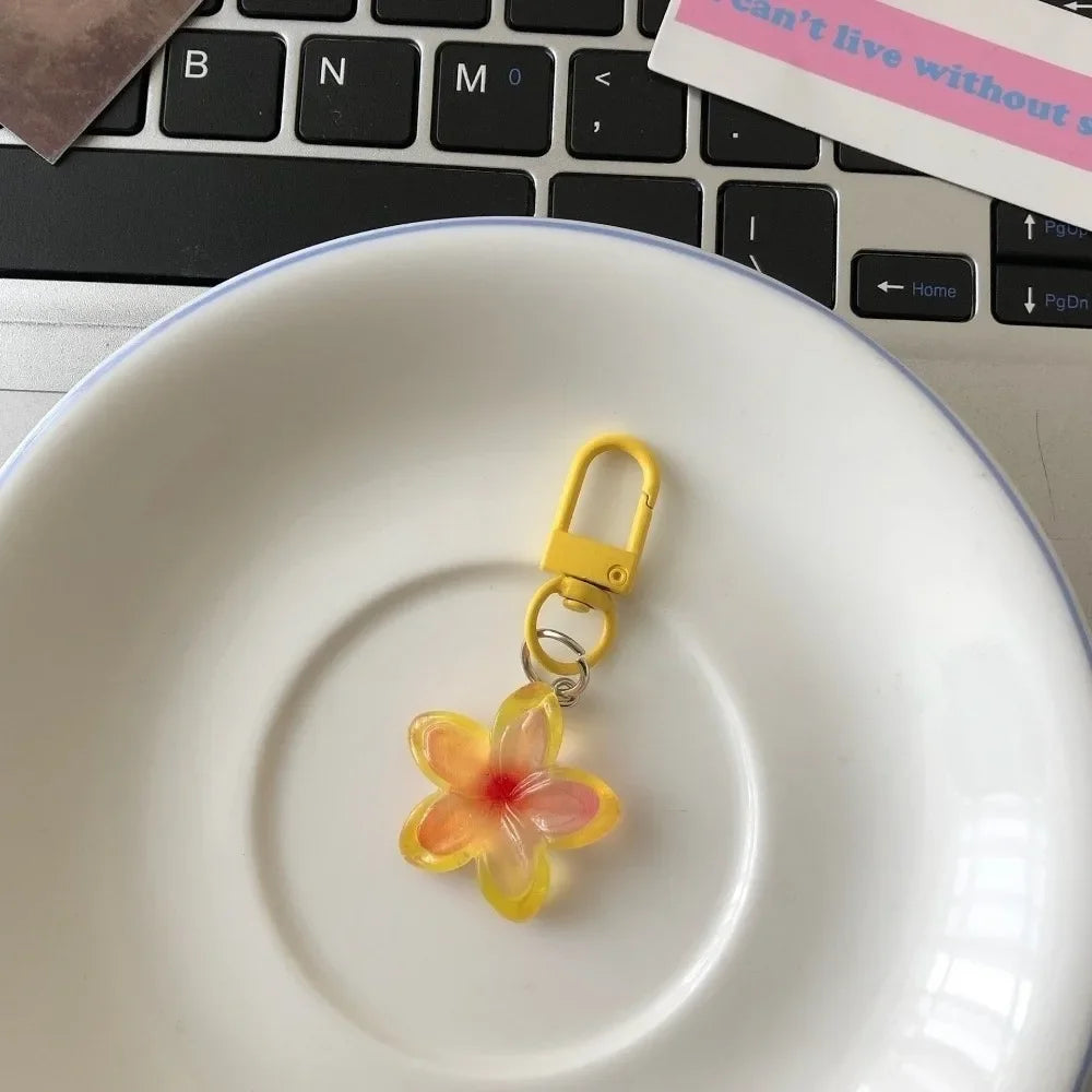 A yellow resin flower keychain resting on a white ceramic plate next to a laptop keyboard.