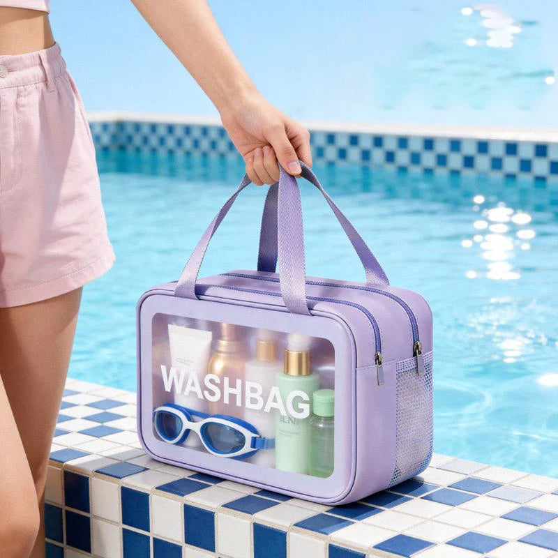 A purple travel toiletry bag with a clear window showing skincare products sits on a tiled surface next to a swimming pool.