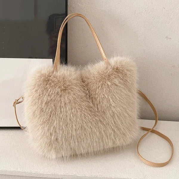 A beige plush faux fur tote bag with a thin gold-toned crossbody strap resting on a light surface.