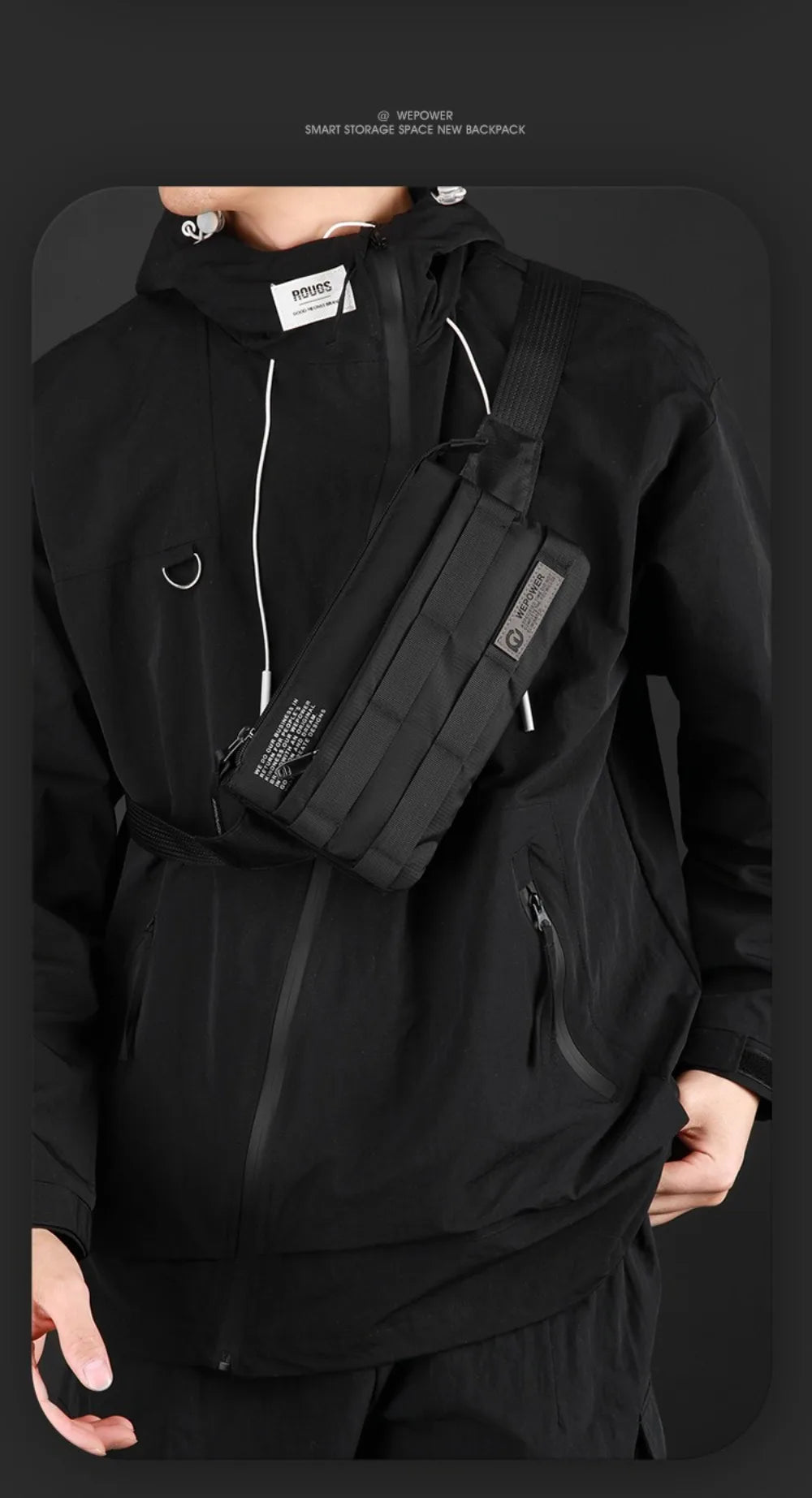 A person wearing a black hoodie holds a black multifunctional chest bag against their body.